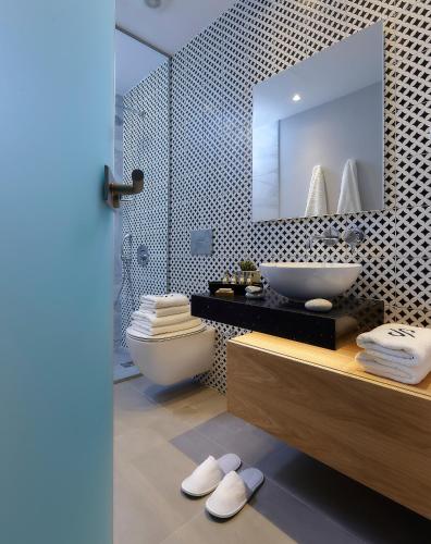 a bathroom with a sink and a toilet and a mirror at Seascape Luxury Residences in Agia Pelagia