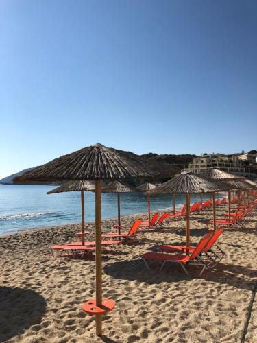 a bunch of chairs and umbrellas on a beach at Seascape Luxury Residences in Agia Pelagia