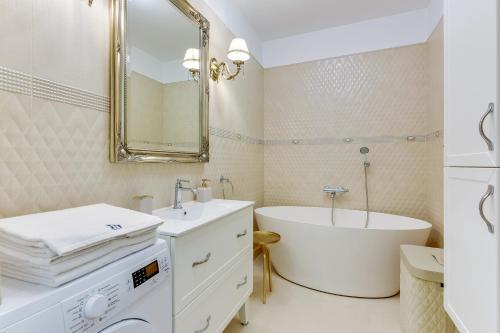 a white bathroom with a tub and a sink at INA Rent - Tre Mare Apartamenty in Gdańsk
