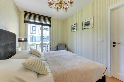 two beds in a bedroom with a chandelier at INA Rent - Tre Mare Apartamenty in Gdańsk