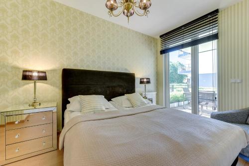 a bedroom with a large bed and a window at INA Rent - Tre Mare Apartamenty in Gdańsk