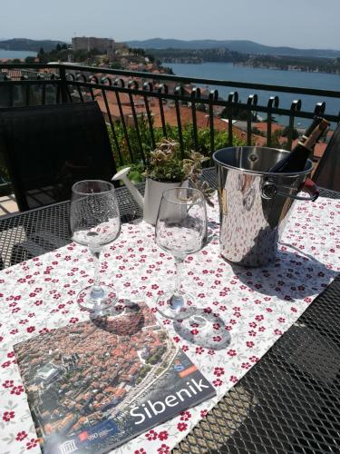 a table with wine glasses and a magazine on it at Apartman Betty in Šibenik