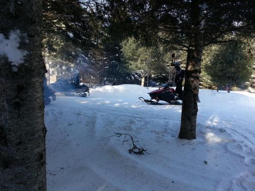 a snowmobile parked next to a tree in the snow at Bed and Breakfast Du Repos in Saint Quentin