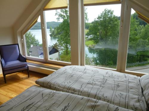 a bedroom with a bed and a large window at Panoramaferienhaus Sorpesee in Sundern