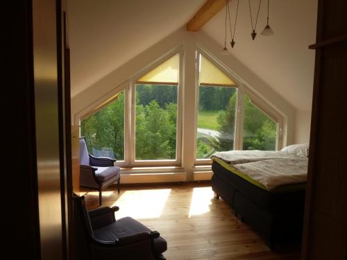 een slaapkamer met een groot raam en een bed en een stoel bij Panoramaferienhaus Sorpesee in Sundern