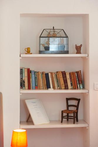 a shelf filled with books with a chair and a bird cage at La Grande Maison De Nans in Nans-les-Pins