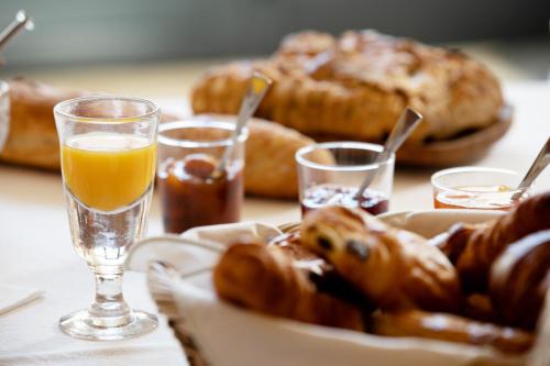 ein Tisch mit einem Teller Gebäck und Gläsern Orangensaft in der Unterkunft L'Hote Antique - MAISON D'HOTE- 4 Suites avec cuisine in Pichanges