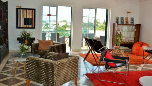 a living room with chairs and tables and windows at Tavira Terrace in Tavira