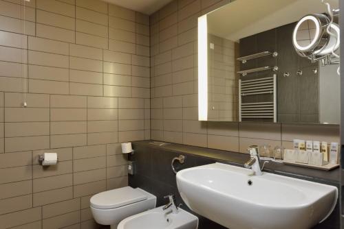 a bathroom with a sink and a toilet and a mirror at Terme Olimia - Hotel Sotelia in Podčetrtek