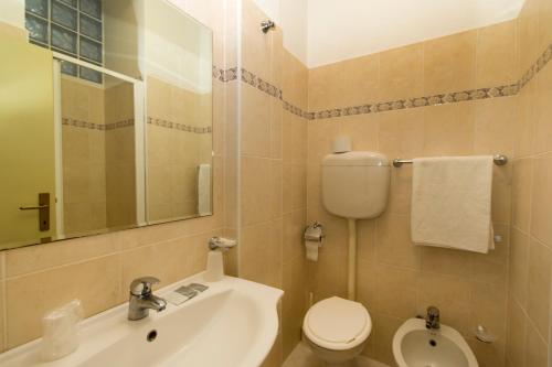 W łazience znajduje się umywalka, toaleta i lustro. w obiekcie Hotel Tre Assi w Rimini
