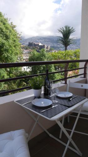 a table with plates and wine glasses on a balcony at Jasmineiro - Palms Palace Apartment in Funchal