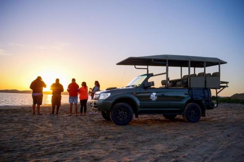a group of people standing next to a truck on the beach at Sundune Guest House in Colchester