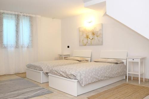 a white bedroom with two beds and a painting on the wall at Apartment Gli Ulivi - Tremezzina in Tremezzo