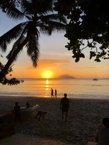 a group of people on the beach at sunset at Flower Garden Self-Catering Apartments in Beau Vallon