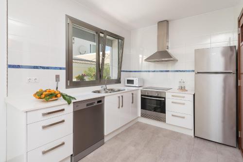 a kitchen with white cabinets and a stainless steel refrigerator at Formentera 1 in Can Picafort