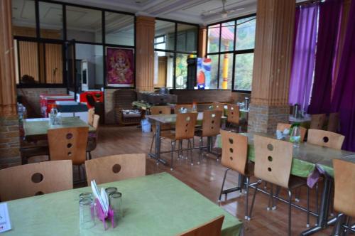 un restaurant vide avec des tables, des chaises et des fenêtres dans l'établissement Hotel Auli D, à Jyotirmath