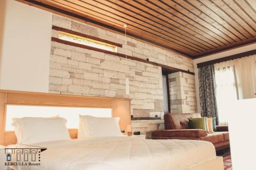 a bedroom with a large bed and a brick wall at KERCULLA Resort in Gjirokastër