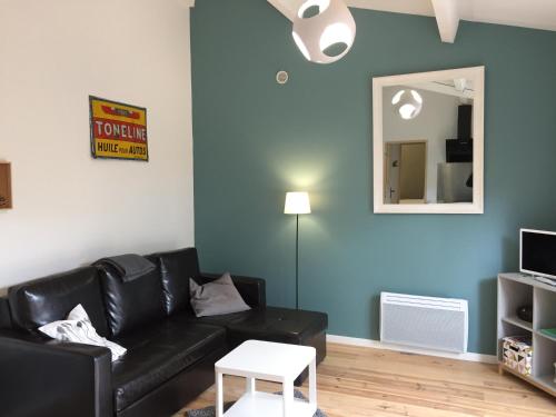 a living room with a black leather couch and a mirror at Fanchon des Sablons in Sarrians