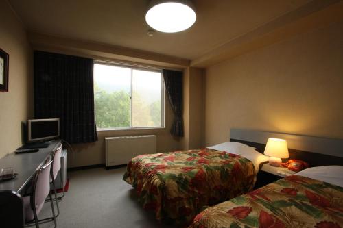 Cette chambre comprend 2 lits et une fenêtre. dans l'établissement Kitashiga Holiday Inn, à Yamanouchi