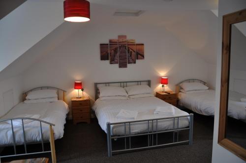 een slaapkamer met 2 bedden, 2 lampen en een spiegel bij Victoria Villa Guesthouse in Clacton-on-Sea