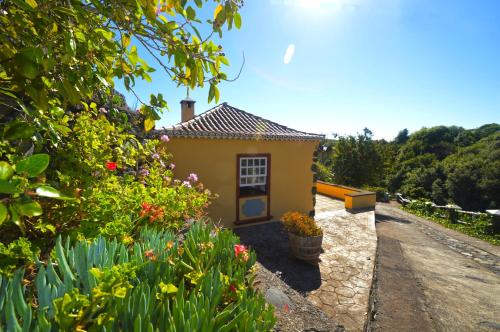 una piccola casa gialla con fiori in un giardino di Emiliana a Puntallana