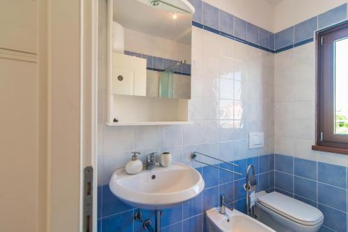 a blue tiled bathroom with a sink and a toilet at Apartment Gordana Ghedda in Nova Vas