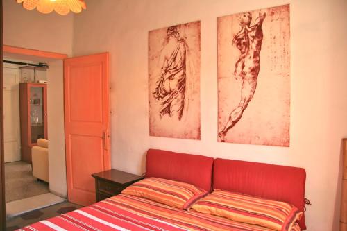 マッサ・マリッティマにあるIl Nidoの赤いベッドと壁に2枚の写真が備わるベッドルーム1室が備わります。