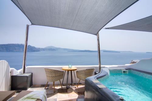 a balcony with a swimming pool and a table and chairs at Secret Legend Suites in Oia