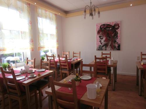 une salle à manger avec des tables et des chaises ainsi qu'une peinture murale. dans l'établissement Hotel Kaufhold - Haus der Handweberei, à Waltrop