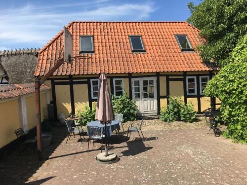 uma casa com um guarda-sol, uma mesa e cadeiras em Millinge Gamle Skole em Millinge