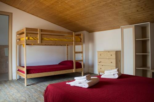 a bedroom with two bunk beds with red sheets at Fontana La Pietra in Pisticci