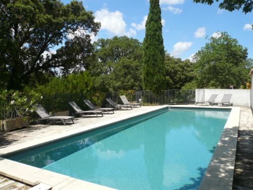 a swimming pool with chairs and a fence at Chambres d'hôtes de la gardy in Eyragues