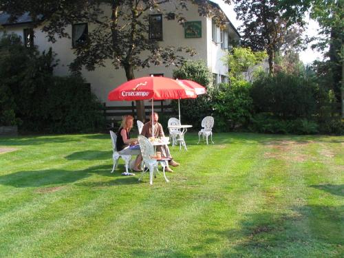 two people sitting at a table under an umbrella at Rothay Garth in Ambleside