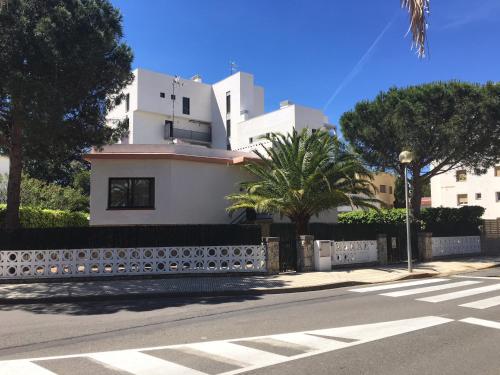 a white building with a fence and trees on a street at Casa Lorca in Roses
