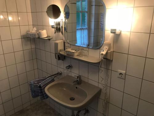 a white bathroom with a sink and a mirror at Hotel Mylos in Sittensen