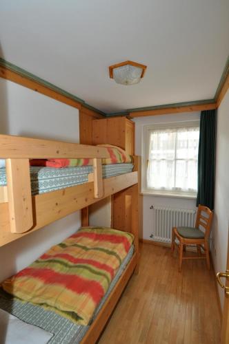 a bedroom with two bunk beds and a chair at Villetta Enrosadira in Vigo di Fassa
