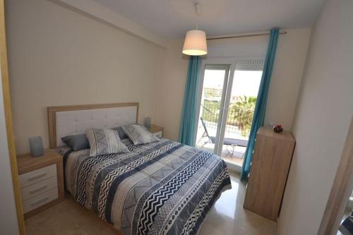 een slaapkamer met een bed en een glazen schuifdeur bij Apartamento Manilva Playa in Manilva