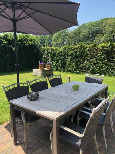 a wooden table with chairs and an umbrella at Hof ter Sysen in Loppem