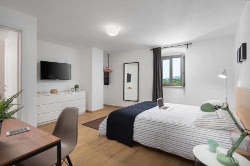 ein weißes Schlafzimmer mit einem Bett, einem Schreibtisch und einem TV in der Unterkunft Lemechi Casa San Marco in Labin