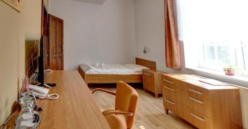 a room with a desk and a bedroom with a bed at Penzion Tillerova vila in Lázně Bohdaneč