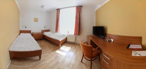 a small room with a bed and a tv at Penzion Tillerova vila in Lázně Bohdaneč