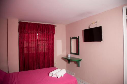 a bedroom with a pink bed and a red curtain at Residencial Turistico Cuba in Panama City
