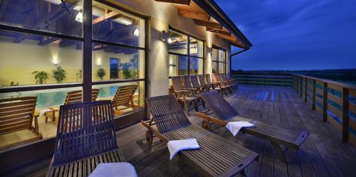 a deck with wooden chairs and a swimming pool at Wellness Hotel Happy Star in Hnanice
