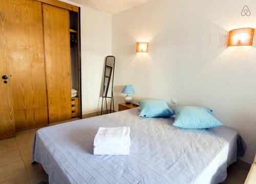 Roja- PéにあるApartamento T1 a 250 metros da Praia - Albufeiraのベッドルーム(青い枕の大型ベッド1台付)