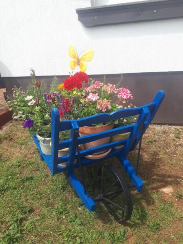 a blue bench with a butterfly on top of flowers at Adriana F. in Dobreć