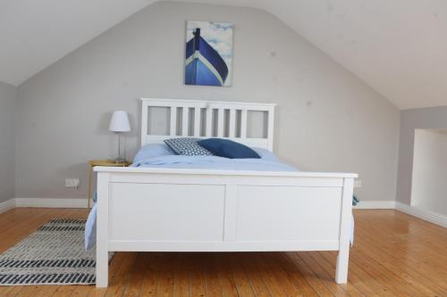 a bedroom with a white bed with a white headboard at Rosaries Apartment Kilkee in Kilkee