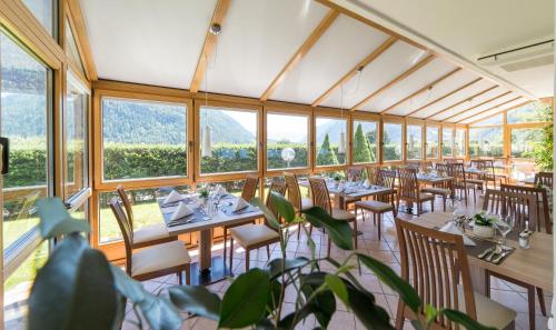 un comedor con mesas, sillas y ventanas en Hotel Mirabell en Campo Tures