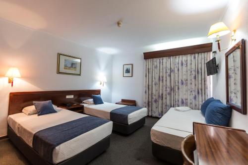 um quarto de hotel com duas camas e uma televisão em Hotel Arangues em Setúbal