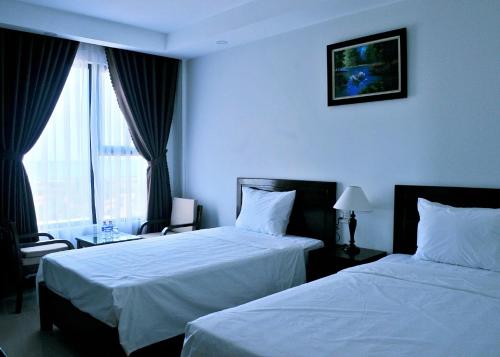 a hotel room with two beds and a window at Aries Hotel in Tuy Hoa