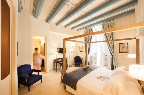 シラクーサにあるアルリア オルティジャ シャルメ ホテルのベッドと椅子付きのホテルルーム
